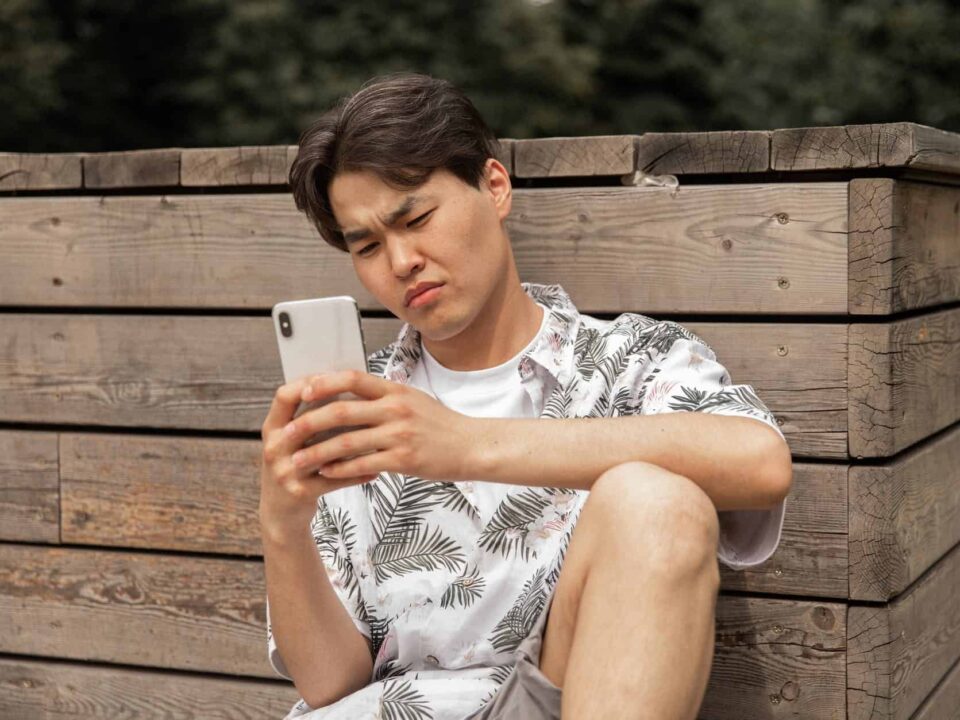 asian displeased man browsing smartphone in countryside