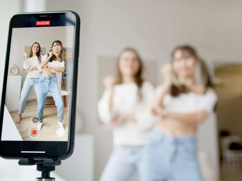 woman in white sleeveless shirt and blue denim skirt holding black smartphone