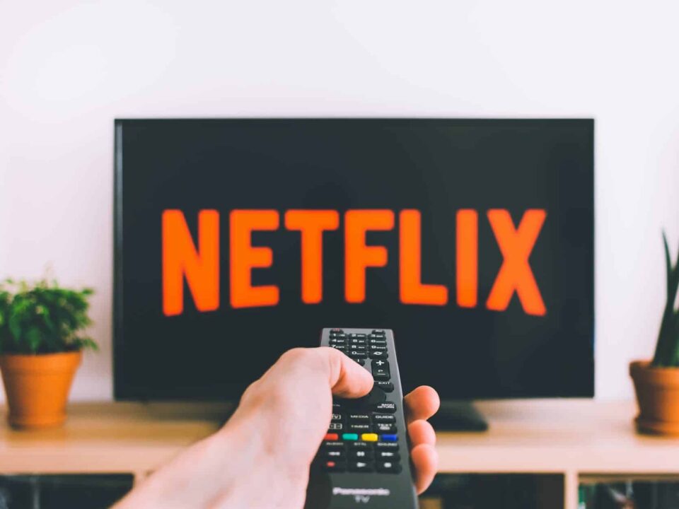 closeup photo of person holding panasonic remote control in front of turned on smart television